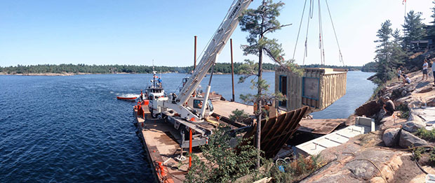 A crane lifting the Grotto Sauna into place